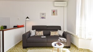 Ein modernes Wohnzimmer mit einer Couch, einem kleinen runden Tisch, einer Lampe und einer Wandklimaanlage.