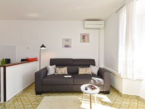 A modern living room with a sofa, a small round table, a lamp, and a wall-mounted air conditioner. - Apartment 1825 by Interhome (Rabac)
