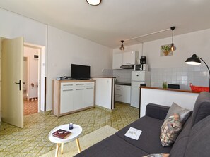 A compact living space with a kitchenette, a sofa, a small table, and a television. - Apartment 1825 by Interhome (Rabac)