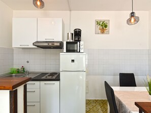 Eine kleine Küche mit weißen Schränken, einer Mikrowelle, einer Kaffeemaschine und einem Spülbecken.