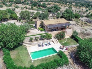 Ein geräumiges Haus mit Swimmingpool, umgeben von viel Grün und einer hügeligen Landschaft.