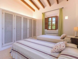 Quarto com duas camas, janela com cortinas e radiador.