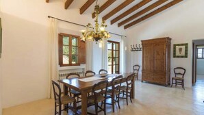 A dining room with a wooden table and chairs, a chandelier, and a wooden cabinet. - Vacation home Calma by Interhome (Sant Llorenç des Cardassar)
