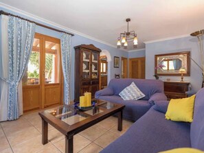 Ein Wohnzimmer mit einer Couch, einem Glastisch, einem Schrank und einer Chandel.