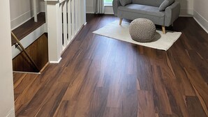 Ein Schlafzimmer im Spitzboden mit schrägem Dach, einem grauen Sofa, einem weißen Teppich und einer Holztreppe.