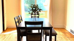 Ein Essbereich mit Tisch und Stühlen, einer Hängeleuchte und Blick durch ein Fenster.