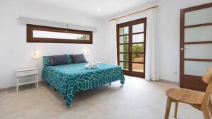 A bedroom with a bed, a chair, a window, and a door. - Vacation home Vivot by Interhome (Búger)