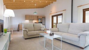 A modern living room with a sofa, a coffee table, and a kitchen in the background. - Vacation home Vivot by Interhome (Búger)