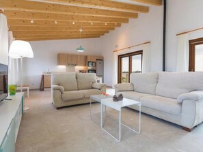 A modern living room with a sofa, a coffee table, and a kitchen in the background. - Vacation home Vivot by Interhome (Búger)