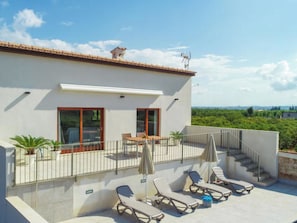 A modern building with a balcony, sun loungers, and a view of greenery. - Vacation home Vivot by Interhome (Búger)