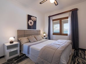 Ein Schlafzimmer mit Bett, Nachttischen, einer Fensterbank und einem Wandbild.