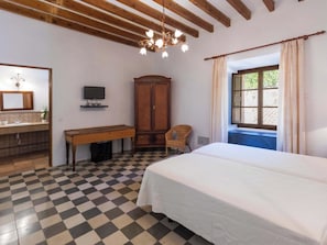 A bedroom with a checkered floor, a bed, a wooden desk, a television, a wardrobe, and a window with curtains. - Caballeria 16 Familiar by Interhome (Bunyola)