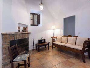 Ein gemütliches Wohnzimmer mit Kamin, einer Couch, einem Sessel und einer Lampe.