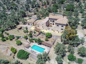 Un grand immeuble à plusieurs étages doté d’une piscine, entouré d’arbres et situé dans un paysage vallonné.
