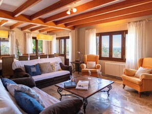 Ein geräumiges Wohnzimmer mit einer Couch, Sesseln, einem Couchtisch und Blick ins Freie.
