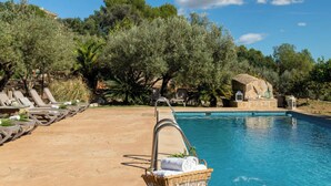 A poolside area with lounge chairs, a stone structure, and lush greenery. - Maribel by Interhome (Inca)