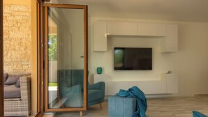 A modern living room with a large TV, comfortable seating, and a glass door leading to an outdoor area. - Villa Markulin by Interhome (Bokordici)