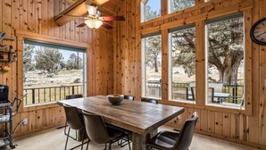 A wooden-paneled room with a dining table, chairs, and a view of a barbecue grill outside. - Eagle Crest Retreat on Golf course, Private w/View (Redmond)