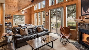 A cozy cabin interior with a leather sofa, dining table, and a fireplace. - Eagle Crest Retreat on Golf course, Private w/View (Redmond)