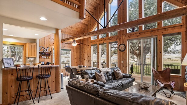 A spacious living area with a leather sofa, a dining table, and a bar area with stools. - Eagle Crest Retreat on Golf course, Private w/View (Redmond)