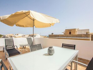 Eine Dachterrasse mit Tisch, Stühlen und einem großen Sonnenschirm.