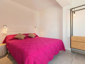 Ein Schlafzimmer mit einem Bett, zwei Nachttischlampen, einem Nachttisch und einer hölzernen Bank.
