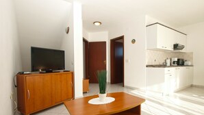 A modern living room with a wooden entertainment unit, a flat-screen TV, a coffee table, and a potted plant. - Apartment 1978 by Interhome (Dracevac)