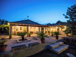 Ein Gebäude mit überdachter Terrasse, Steinstufen und Blumentöpfen.