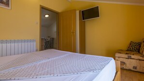 A bedroom with a bed, a television mounted on the wall, and a wooden chest of drawers. - BOZIDAR 1 zuti / HR-10438-01 by Interhome (Selce)