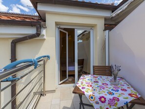 A small balcony with a table, chairs, and a vase with flowers. - BOZIDAR 1 zuti / HR-10438-01 by Interhome (Selce)