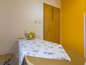 A room with a bed, a small table with a fruit basket, a chair, and a door. - BOZIDAR 1 zuti / HR-10438-01 by Interhome (Selce)