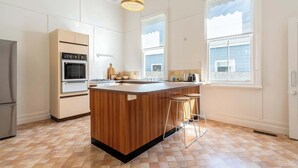 Een moderne keuken met een houten keukeneiland, inbouwapparatuur en grote ramen.