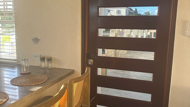 Un coin repas avec une table en bois, des chaises et une porte en bois foncé dotée d’une fenêtre.