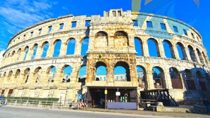 Un amphithéâtre en pierre d’époque, doté de nombreuses arcades et d’une entrée centrale.