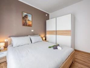 Une chambre à coucher moderne avec un grand lit, une table de chevet avec une lampe, un tableau au mur et un plancher en bois.