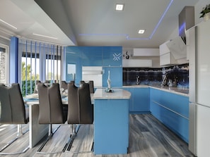 Une cuisine moderne avec des meubles bleus, un îlot central et un coin repas avec des chaises.