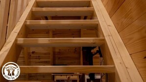 A wooden staircase with a rope handrail, leading to a room with a wooden ceiling and walls. - Le Chalet du Pastoureau (BESSE ET SAINT ANASTAISE)