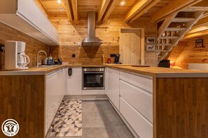 Eine moderne Küche mit Holzbalken, einem eingebauten Backofen und einer Kaffeemaschine.