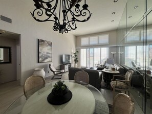 Una sala de estar moderna con comedor, televisor y candelabro.