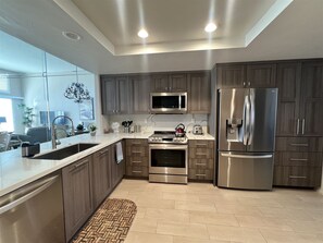 Una cocina moderna con refrigerador de acero inoxidable, microondas, horno y pileta.