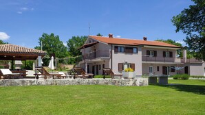 A two-story house with a balcony, a patio area with lounge chairs, and a stone wall. - Villa Morena by Interhome (Jakovici)