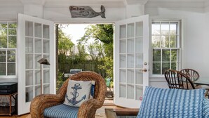 A room with a wicker chair, a blue patterned sofa, and a wooden table. - Pau Hana - Spacious 4-bedroom house in quaint Nantucket with AC (Nantucket)