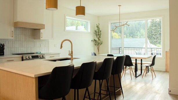 Una cocina moderna con una isla grande, taburetes de bar e iluminación colgante.