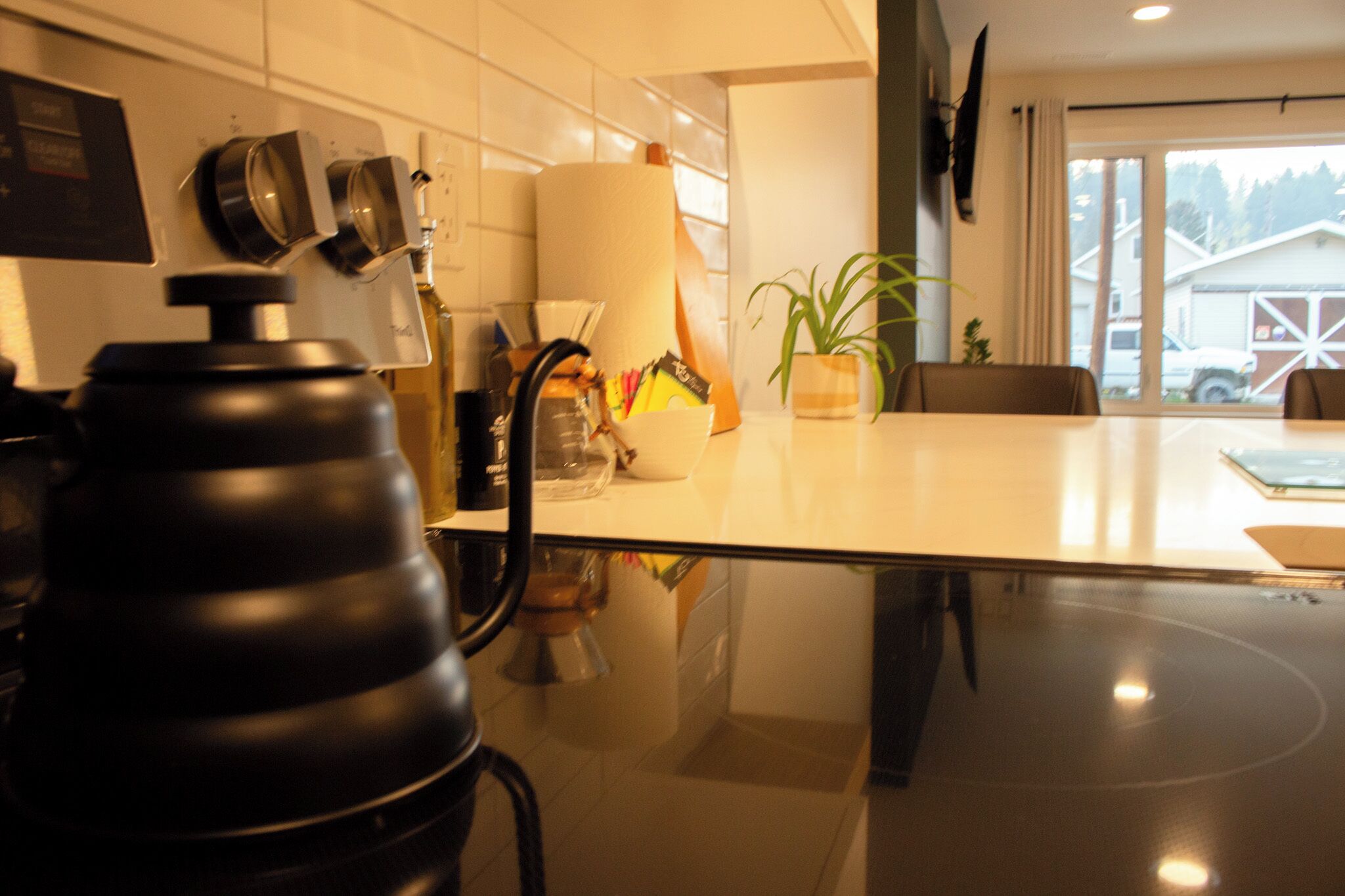 Een moderne keuken met een zwarte blender, een grote witte lamp en een potplant op het aanrecht.