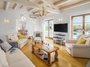A spacious living room with a wooden ceiling, a large TV, and a dining area with a table and chairs. - Villa Kanco by Interhome (Pula/Manjadvorci)