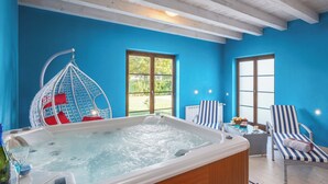Ein Zimmer mit Whirlpool, Hängesessel und zwei Streifenstühlen.