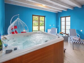 Ein Zimmer mit Whirlpool, Hängesessel und zwei Streifenstühlen.