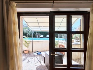 Ein Zimmer mit einer Schiebetür zu einer Terrasse mit Pool, Gartenmöbeln und einer Pflanze in einem Topf.