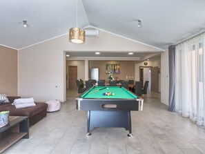 Una sala de estar moderna con mesa de billar, un sofá y un comedor.