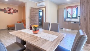 A dining area with a wooden table, chairs, and a vase with flowers. - Villa Amber by Interhome (Pula/Manjadvorci)